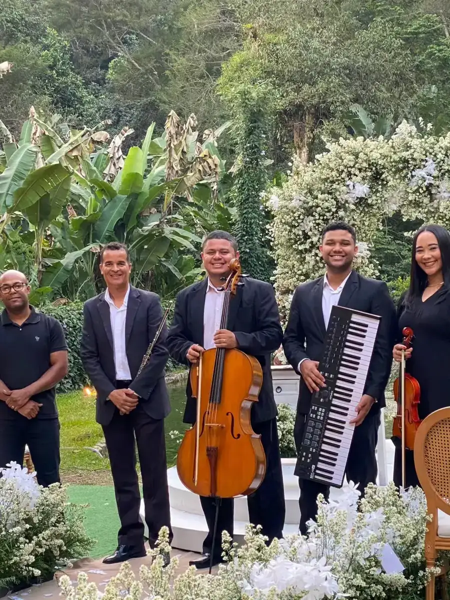 Músicos da First Symphony com violoncelo, flauta, teclado e violino em altar de casamento decorado com flores brancas